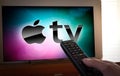 Barcelona, Spain. January 2019: Man holds a remote control With the Apple TV icon screen on TV