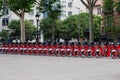 Red bicycles available for rent parked in a row at Passeig de Lluis Companys. Concept of environmentally sustainable transport.