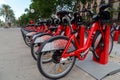 Red bicycles available for rent parked in a row at Passeig de Lluis Companys. Concept of environmentally sustainable transport.