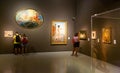 Visitors of national museum of Catalan visual art viewing paintings