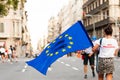 Barcelona, spain- 17 july 2019: young woman walks in the streets in daylight holding european union flag with blood stains on it