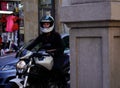 Young biker woman with integral helmet and radical sports motorcycle waits on busy street.