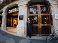 Young stylish woman smoking and using the mobile phone smartphone near the entrance of the luxury Massimo Dutti