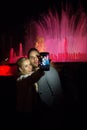 BARCELONA, SPAIN- NOVEMBER 28, 2014: Two unknown young people in the evening at the musical fountains photographing selfie