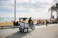 BARCELONA, SPAIN - OCTOBER 15, 2018: Man driving tuk-tuk car. People walking on the Barcelona beach. Summer vacations travel. Royalty Free Stock Photo