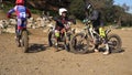 two aged men are sitting on motorcycles amid motocross competitions.