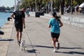 Barcelona, Spain - 26th October 2019: Young couple of runners with a dog in Port of Barcelona, Spain