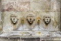 Barcelona. Three ancient stone faces in fountain. Royalty Free Stock Photo