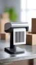 Barcode printer with printed label displaying black and white stripes, positioned on a table with cardboard boxes in a bright Royalty Free Stock Photo