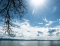 Great sky with clouds and full sun over big lake with mountains