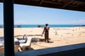 Bare-chested asian senior fisherman stands on the beach