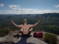 Bare-chested man sit on peak over mountains. Shirtless man