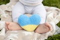 bare feet of a baby and a knitted yellow-blue Ukrainian heart