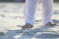 Bare feet of a child in white pants on the sand Royalty Free Stock Photo