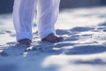 Bare feet of a child in white pants on the sand Royalty Free Stock Photo