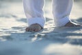 Bare feet of a child in white pants on the sand Royalty Free Stock Photo