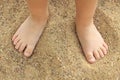 Bare feet of a child on the yellow sand in summer. Royalty Free Stock Photo