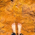 Bare feet for comaprison with orange mineral of natural water spring in Damia