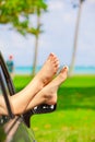 Bare feet of female sticking out car window, by ocean