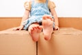 Bare feet of a girl sitting on a pile of cardboard