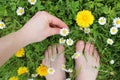 Bare feet and hand on spring grass, flowers Royalty Free Stock Photo