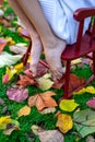 Bare feet of a young girl on a chair on an autumn background