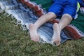 Bare feet and legs of a young person lying stomach down on a woven blanket on the grass at an outdoor concert Royalty Free Stock Photo