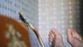 Bare feet raised by man near guitar neck against room corner