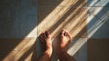 Bare feet on sunlit tiled floor with shadow patterns and warm tones Royalty Free Stock Photo