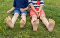 bare feet of two children sitting in meadow. Small flowers stick out among toes Royalty Free Stock Photo