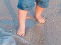 Bare feet walking at sandy beach near the sea. Little baby in blue jeans shorts going to touch the sea at sunset. Wave Royalty Free Stock Photo