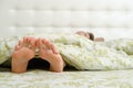 Bare female feet sticking out from under the blanket