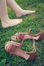 Bare female legs on grass near stand sandals. tinted Royalty Free Stock Photo