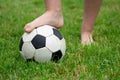 Bare foot of a girl on the soccer ball in green grass Royalty Free Stock Photo