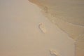 Bare foot step mark on sand beach by sea water tide. Lonely traveler barefoot steps. Clear seawater on sand beach Royalty Free Stock Photo