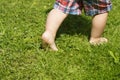Bare foots of the running toddler in the green summer grass