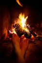 Bare legs of young woman are heated by open fire in fireplace Royalty Free Stock Photo