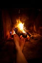 Bare legs of young woman are heated by open fire in fireplace Royalty Free Stock Photo