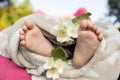 bare little feet of a sleeping baby and delicate white flowers wrapped in a soft blanket