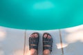 Bare male feet in slippers by the poolside