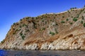 Bare rock in the Mediterranean with ancient stone walls of Alanya Castle on top Turkey. Brown-orange mountain with rare green