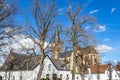 Bare trees with houses with white walls and St. Michael\'s Abbey church with its bell tower in background Royalty Free Stock Photo