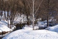 Bare trees and snowdrifts on the banks of a quiet winding forest river  background Royalty Free Stock Photo