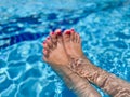 Bare woman feet over blue swimming pool water Royalty Free Stock Photo