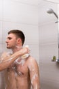 Bare young male rubbing himself a foam sponge bath in shower cab