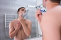 Bare young man shaving his chest and looking at the mirror