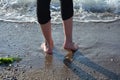 Feet before a wave on the sandy beach Royalty Free Stock Photo