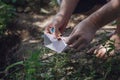 A barefoot adult man lights a paper boat