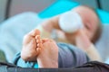 Barefoot baby drinking milk from bottle