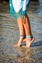 Barefoot boho woman legs in river shallow with ankle bracelet and toe rings white dress